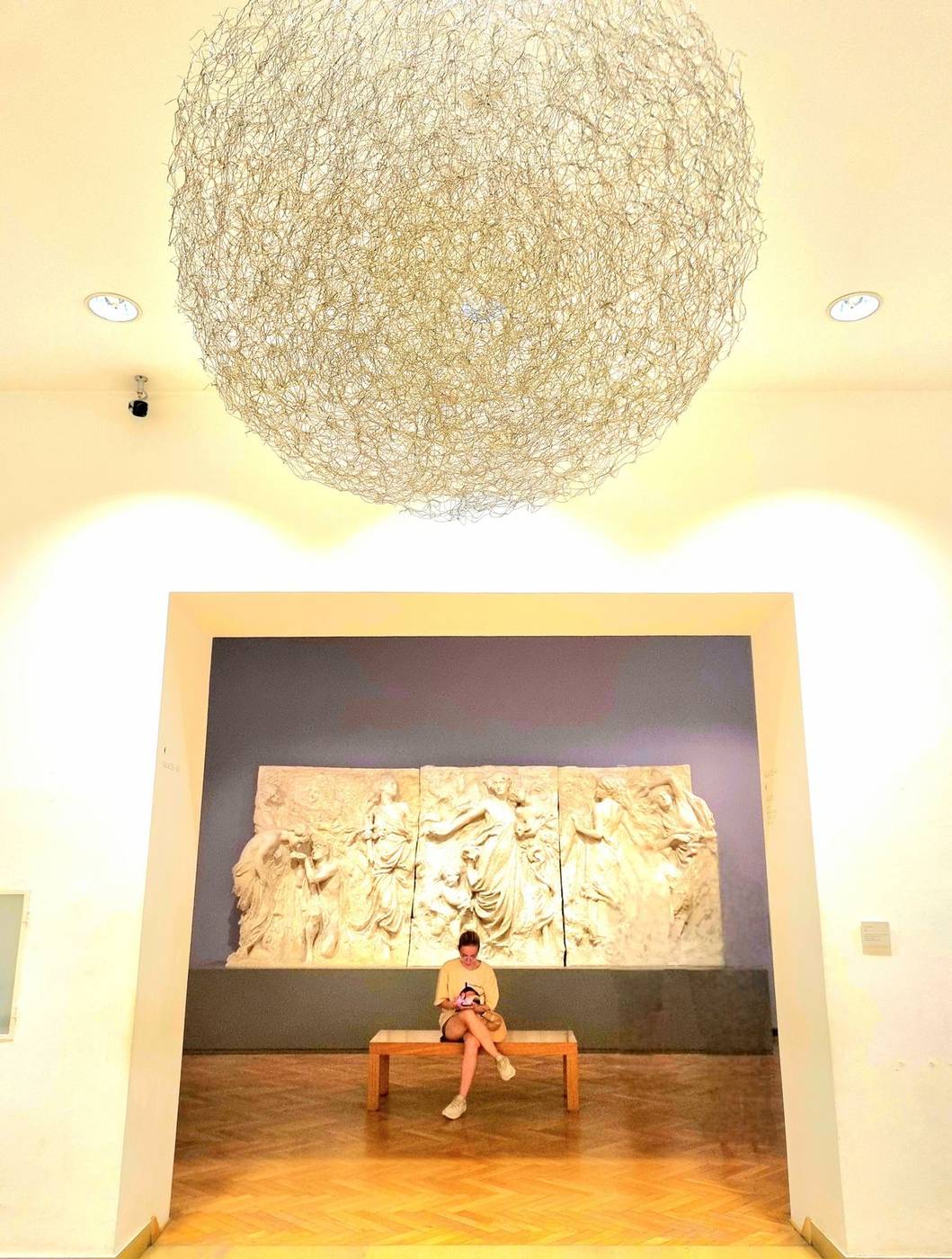 Adriana Kaprielan sentada en un banco del museo, relieve de fondo